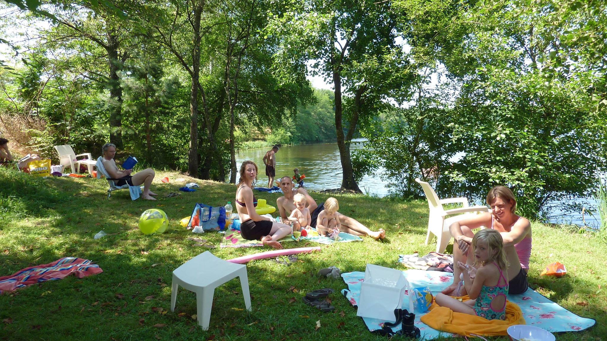 Spelende en picknickende mensen op een grasveld aan het water