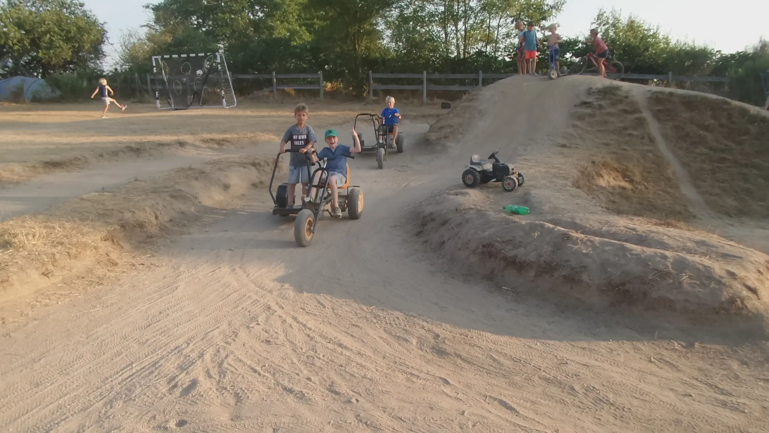 Spelende kinderen op skelters en op een voetbalveldje